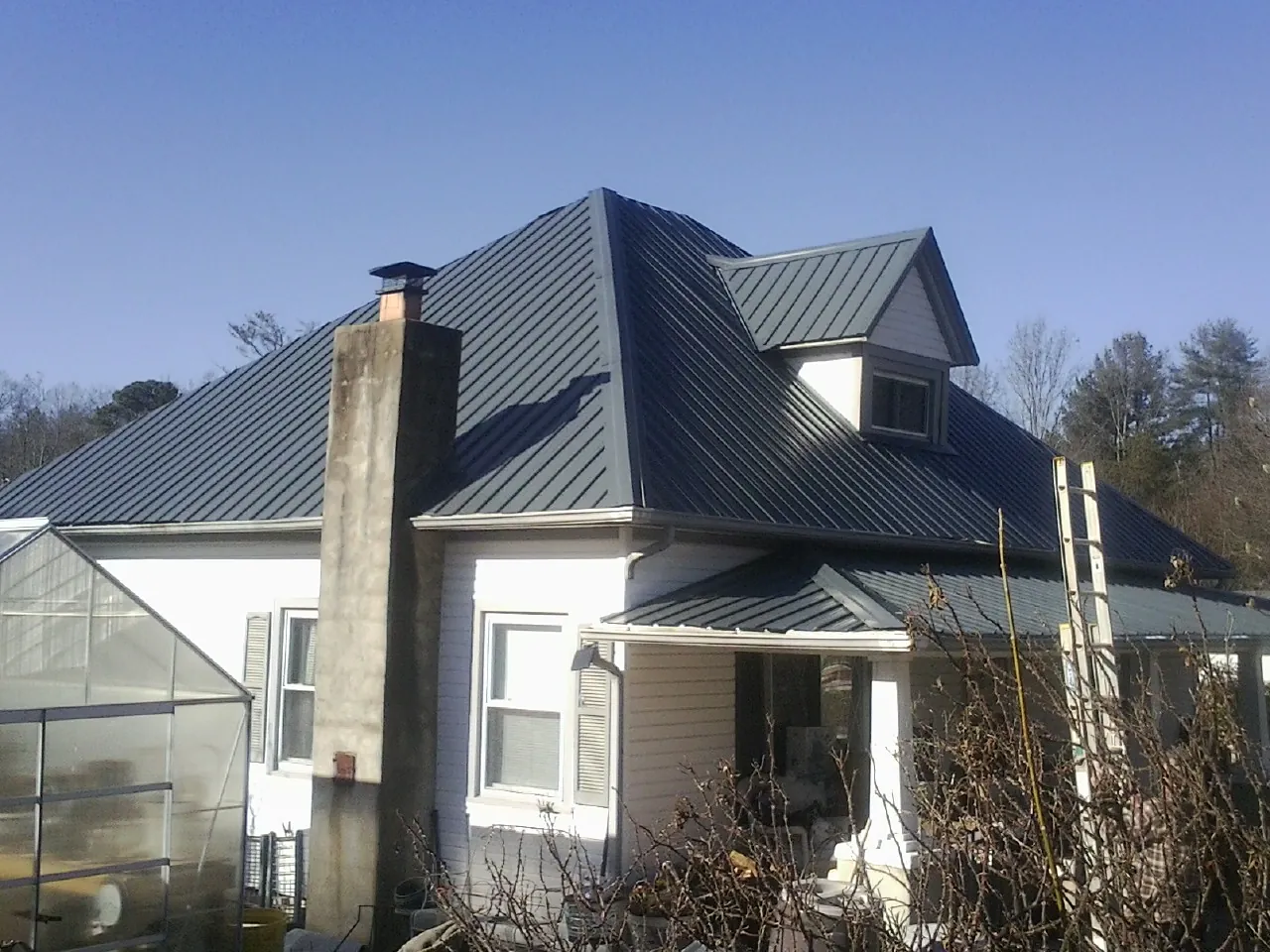 Dark blue standing seam metal roof on a white farmhouse with dormer — Slate & Tile Roof Repair by Roofing Brothers in Oracle