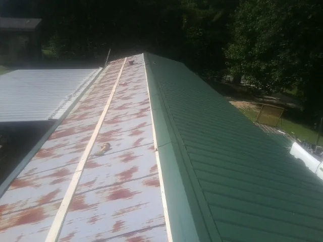 Old rusted panels beside newly installed green metal roofing — Wind Damage Roof Repair by Roofing Brothers in Oracle