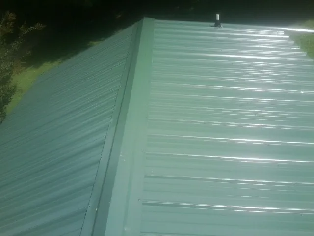 New green metal panels meeting at the ridge of a roof — Flat Roof Repair work by our crew in Oracle
