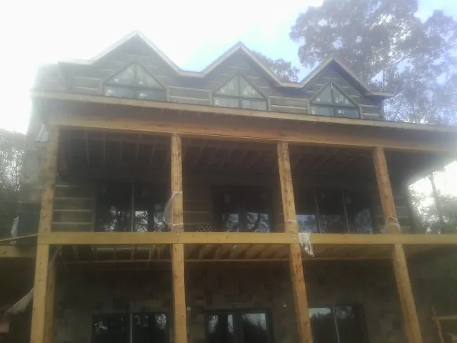 Dormers and porch framing on a large log home under construction — Roof Coating work by our crew in Oracle