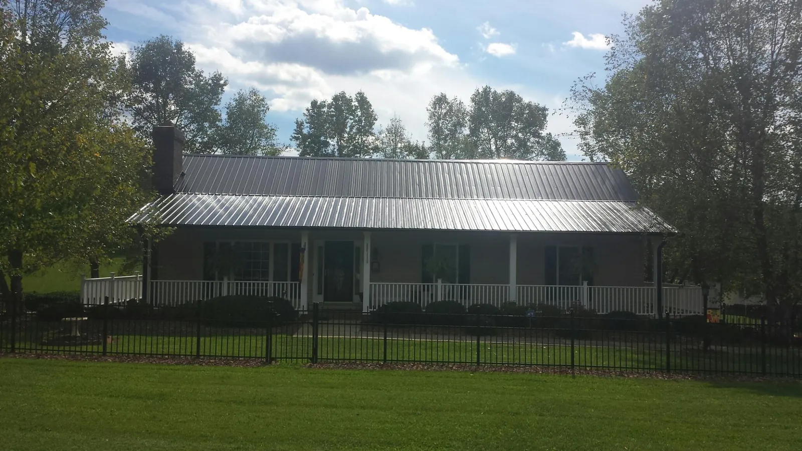 Gray metal roof on a brick ranch with a full width front porch — Gutter Guard Installation work by our crew in Oracle