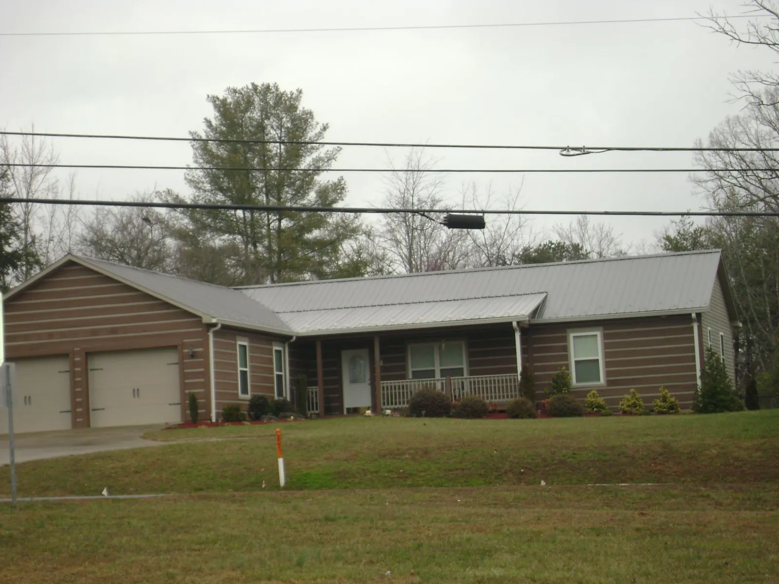 Gray metal roof on a log sided ranch home with a front porch in Oracle