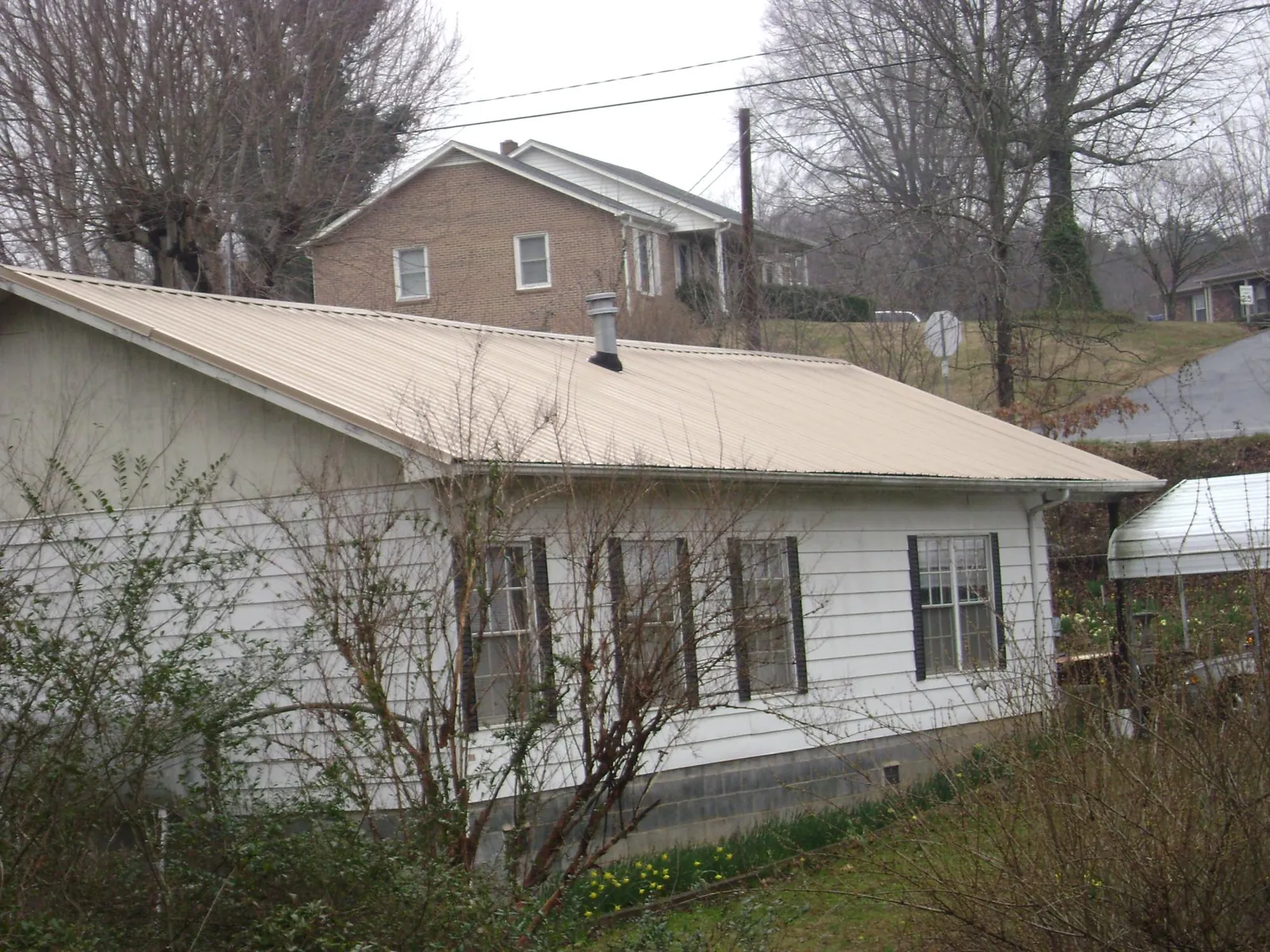 Tan metal roof on a white sided house set into a hillside — Commercial Roofing by Roofing Brothers in Oracle