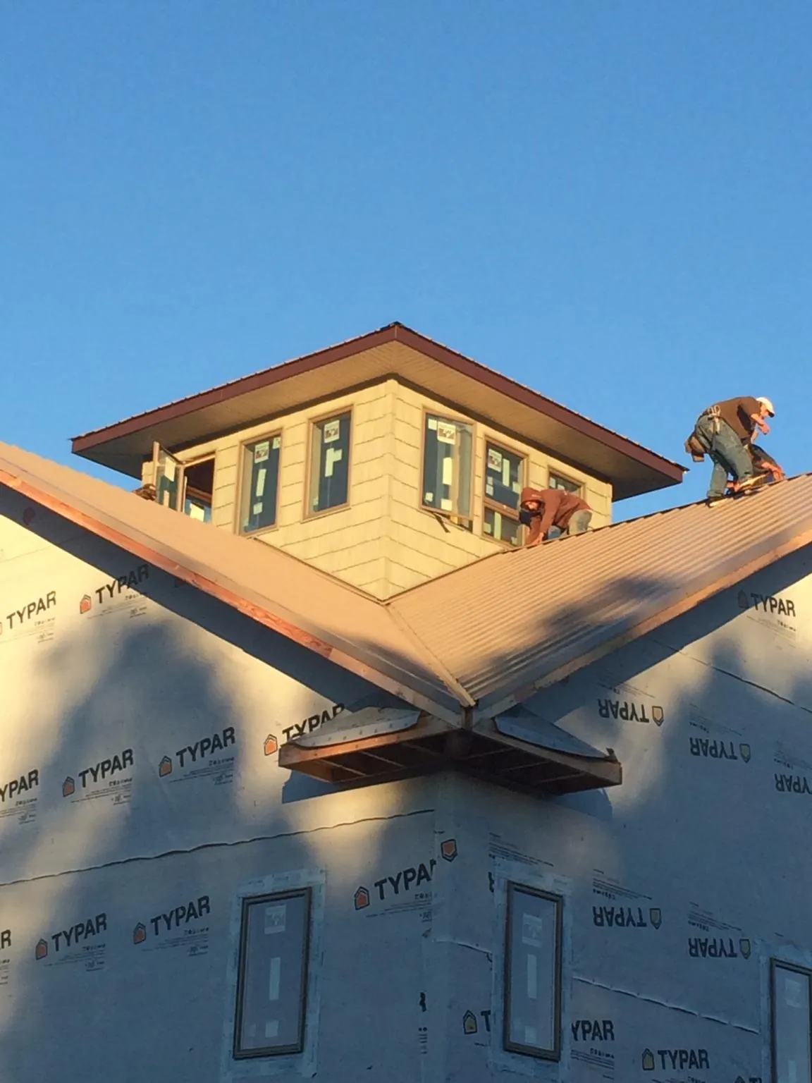 Roofers working around a rooftop cupola on a new metal roof at sunset — Roof Waterproofing in Oracle by Roofing Brothers
